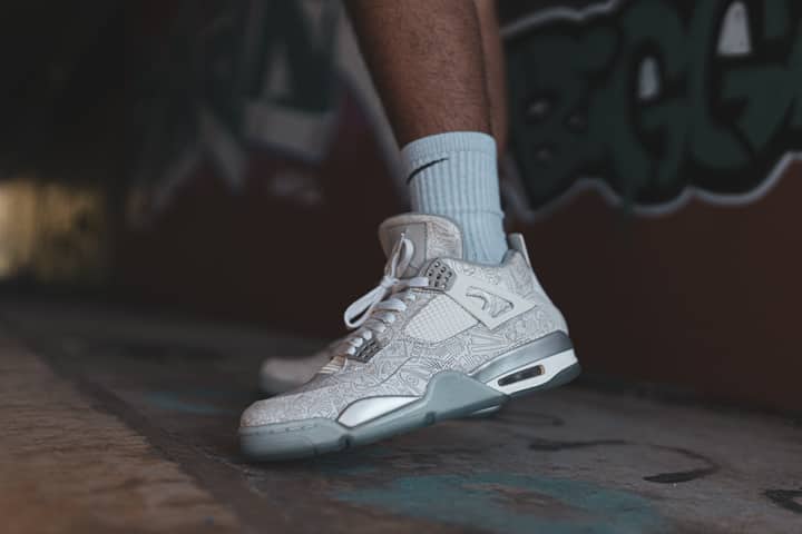 Close-up of designer white sneakers against urban graffiti backdrop.