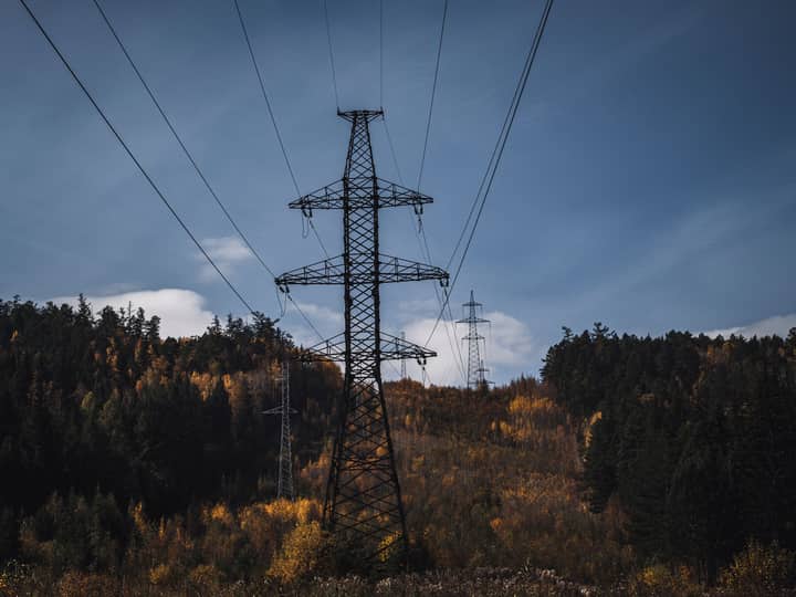 A picturesque autumn scene with transmission towers and colorful forest backdrop.