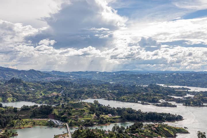A breathtaking aerial view of the lakes and rolling hills in Guatapé, Antioquia, Colombia, under a dramatic sky.