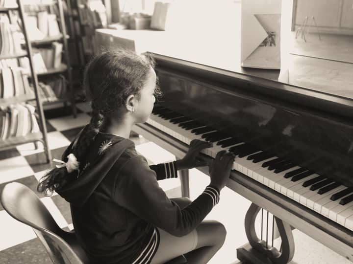 A young girl practicing piano indoors in a cozy setting, focused and serene.