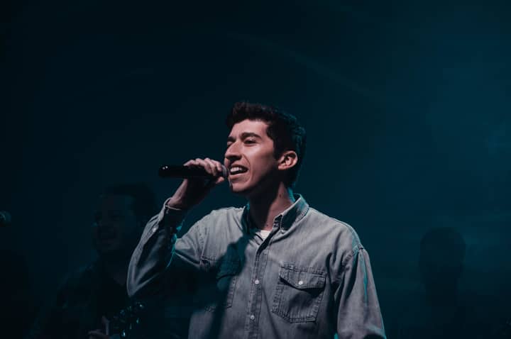 Young male singer performing passionately with microphone on stage. Captured in Mendoza, Argentina.