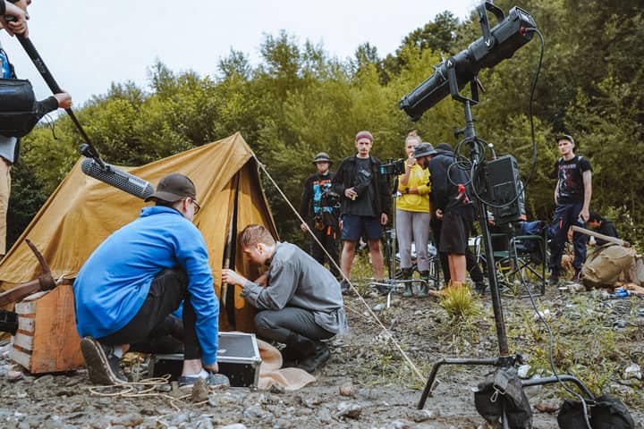 Film crew setting up an outdoor scene with a tent and professional gear.