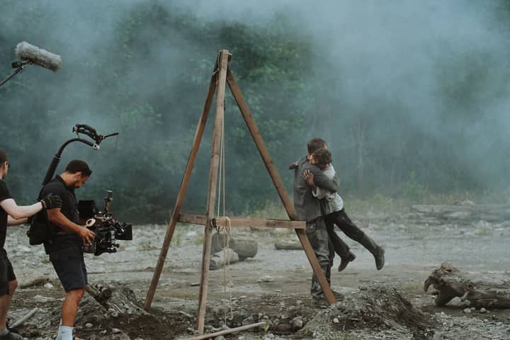 Cinematic embrace captured on a film set amidst smoke outdoors.