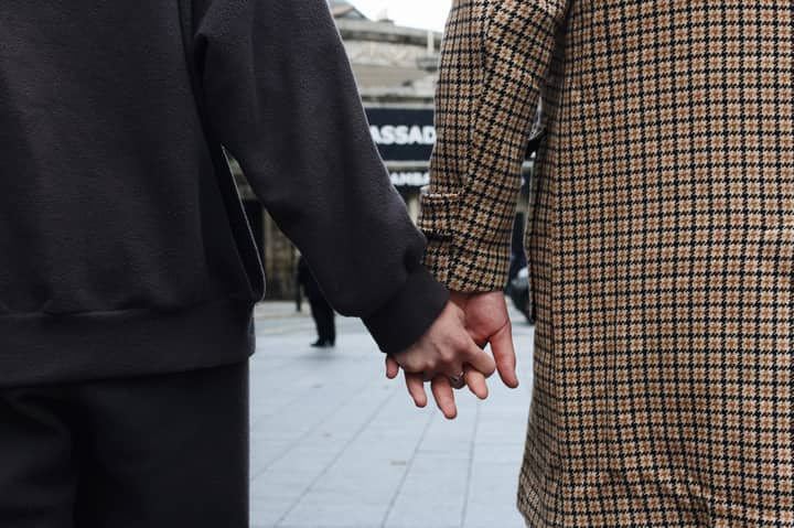Close-up of a couple holding hands on a city street, signifying togetherness and connection.