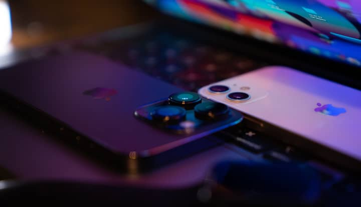 Close-up image of two modern smartphones placed on a laptop keyboard, highlighting technology design.
