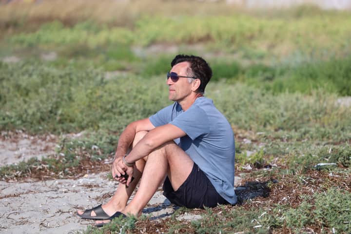 Middle-aged man in blue shirt relaxing outdoors on a sunny day. Casual summer vibe.