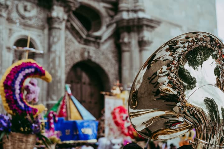 Festival scene in Oaxaca with reflection on a musical instrument, showcasing vibrant traditional culture.