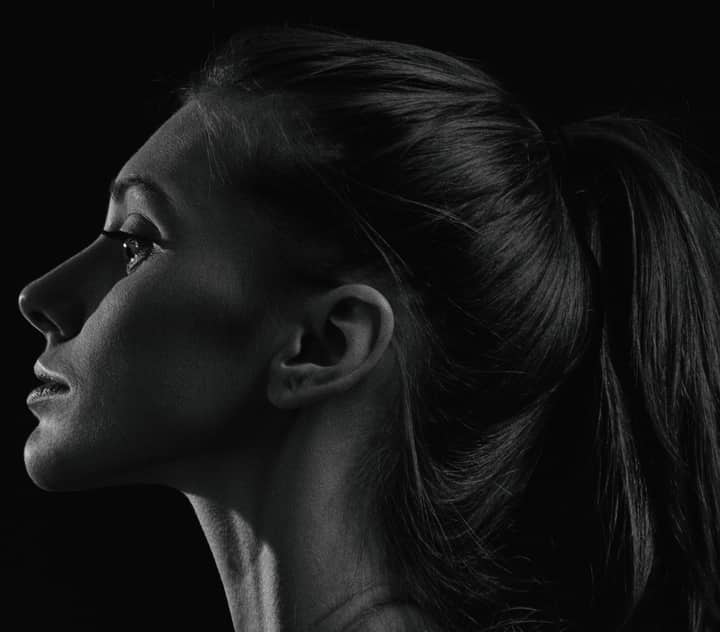 Elegant black and white side profile portrait of a woman with a ponytail.