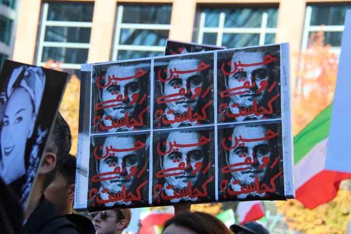 A group of protestors holding signs in a vibrant demonstration on a city street in Vancouver, Canada.
