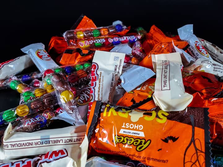 A vibrant stack of colorful Halloween candy wrappers showcasing a variety of sweet treats.