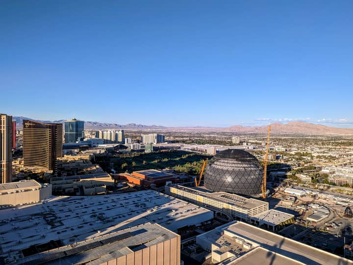 A breathtaking aerial view of Las Vegas with a prominent sphere-shaped landmark and clear blue skies.