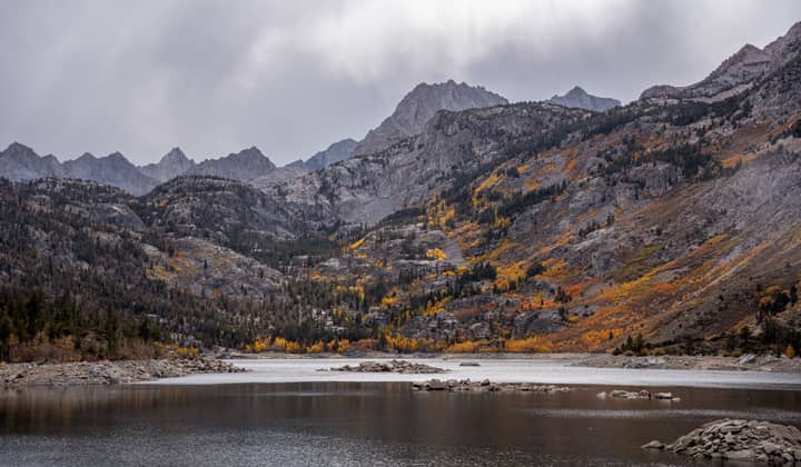 A breathtaking view of Lake Sabrina surrounded by autumn foliage and rocky mountains in Bishop, California.