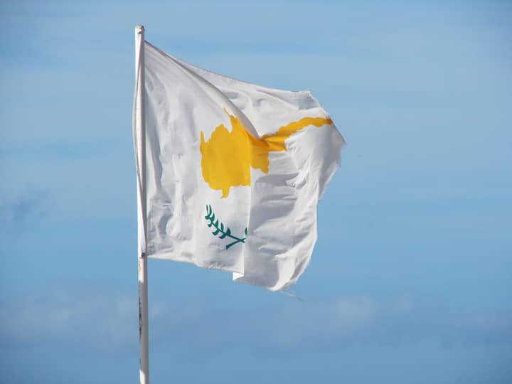 The national flag of Cyprus waving in the breeze against a clear blue sky.