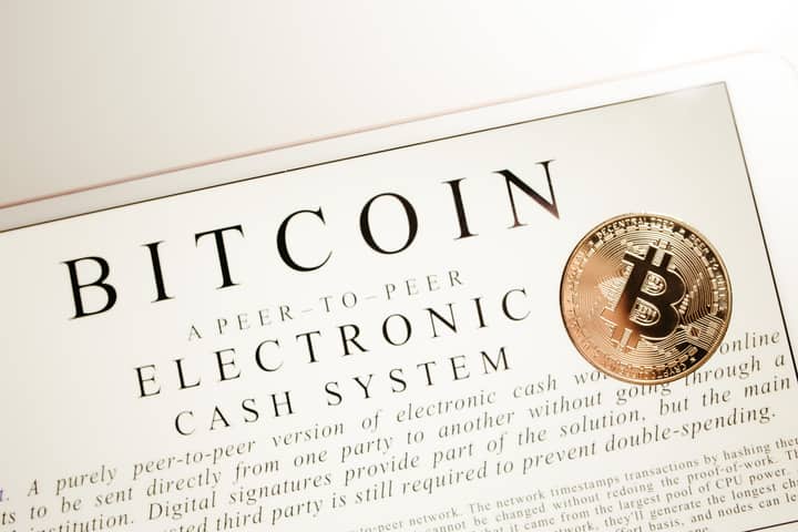 Image depicting Bitcoin electronic cash system with a physical Bitcoin coin prominently displayed.