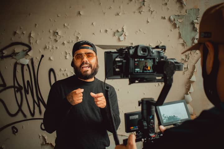 Hip-hop artist passionately performing during an indoor music video recording session.