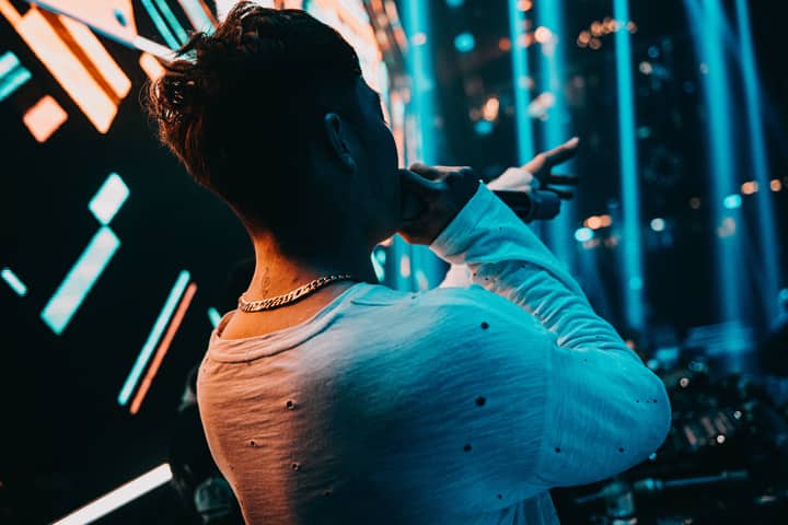 Back view of a singer performing energetically on stage at a vibrant concert.