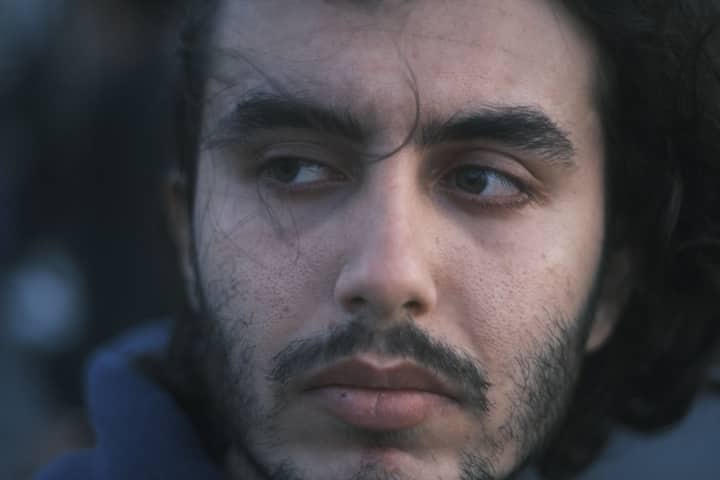 Close-up portrait of a man gazing sideways with a contemplative expression.