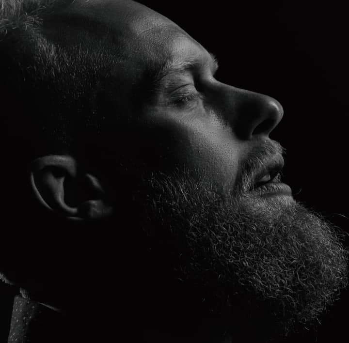 Black and white close-up of a bearded man in side view, capturing emotion and texture.