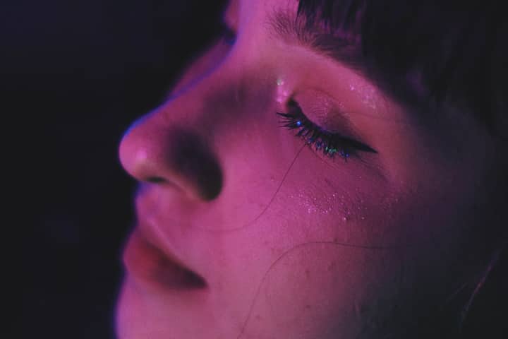 Close-up portrait of a woman with creative eye makeup and euphoria-inspired lighting.
