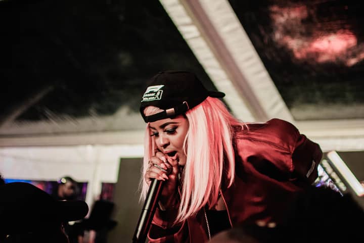 Vibrant live performance of a charismatic female rapper engaging with the audience.