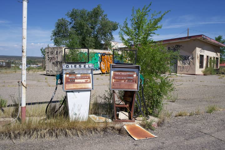 Explore the decay of an abandoned gas station with rusted fuel pumps and grafitti-covered walls.