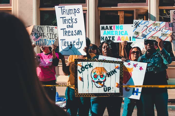 Protesters rally on Wheeling streets holding political signs and banners in a vibrant demonstration.