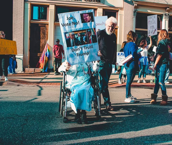 A diverse group of people protesting outdoors with signs and banners in a vibrant street scene.