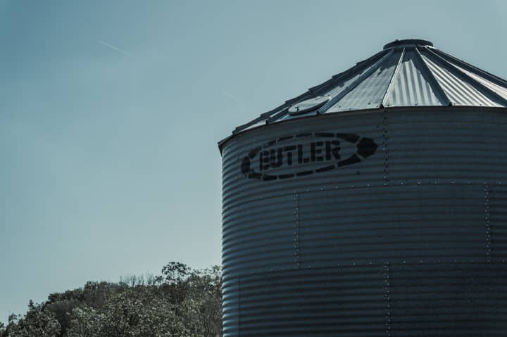 Silhouette of a corrugated metal grain bin against the sky, highlighting rural storage facilities.