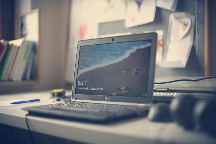 A contemporary workspace featuring a Dell laptop, books, and stationery on a desk, reflecting modern office essentials.