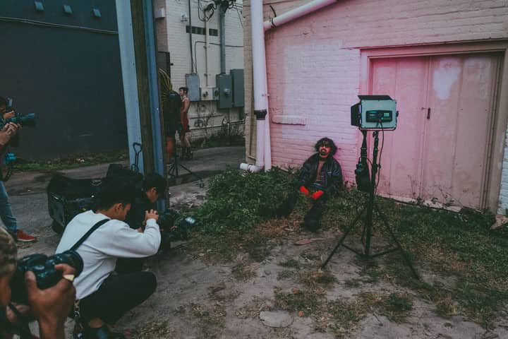 Outdoor photoshoot capturing street style modeling with photographers and lighting equipment.