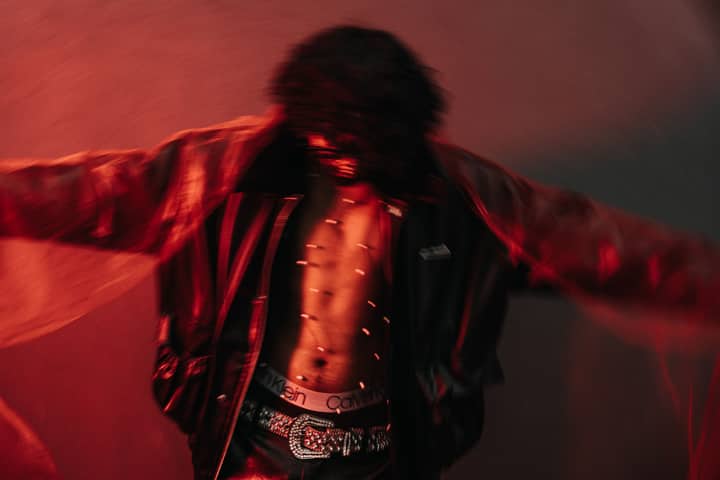 Blurred artistic portrait of a person with red lighting, creating a dramatic effect.
