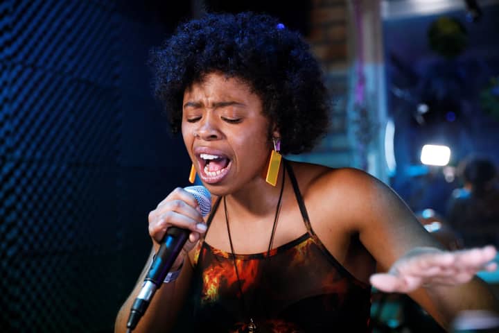 Vibrant performance by a black female singer in a London music venue.