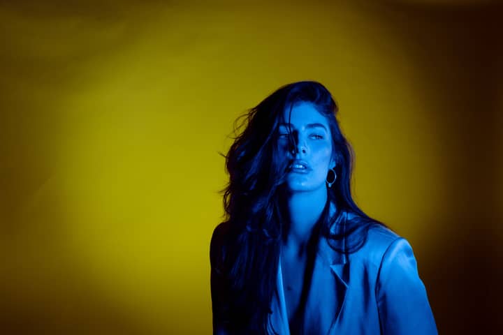 Striking studio portrait of a woman with dramatic blue and yellow lighting.