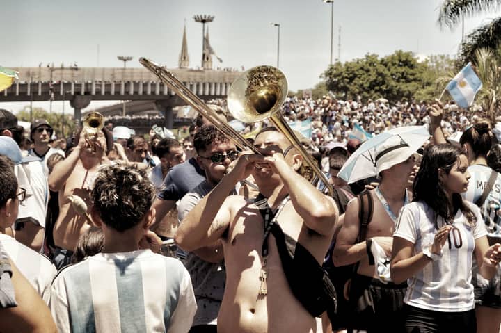 Lively street celebration in Buenos Aires with musical instruments and sports fans.