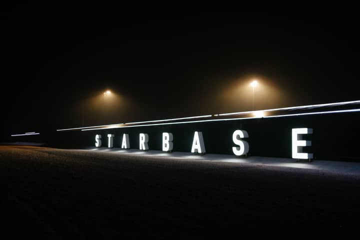 Spacex's Starbase sign glowing vividly in a foggy night setting in Brownsville, Texas.