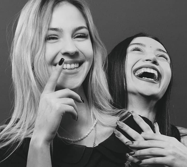 Black and white portrait of two women laughing joyfully, expressing friendship.