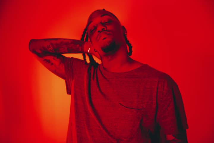 Artistic portrait of a man with tattoos under moody red studio lights.