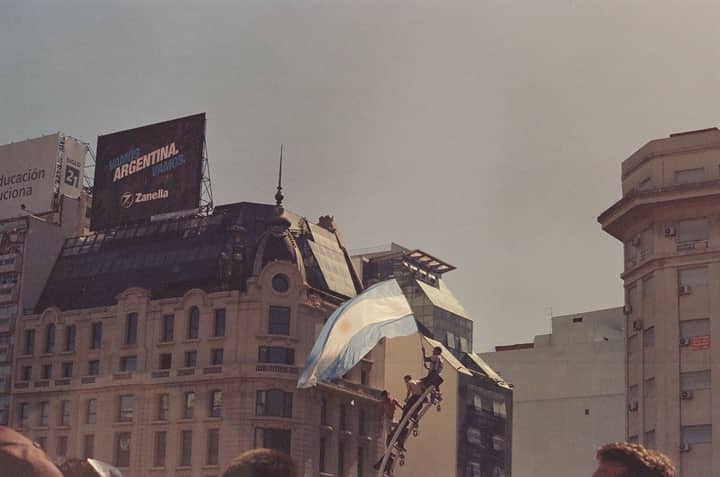 Crowd celebrating in Buenos Aires with Argentine flags, capturing urban excitement.