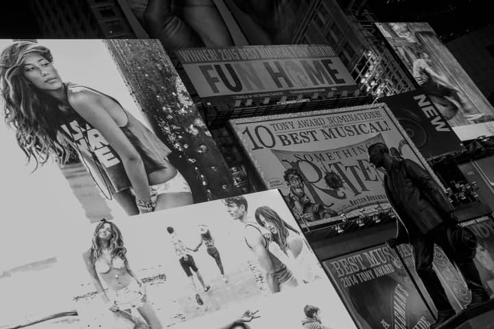 A black and white image of city billboards and a statue in an urban setting.