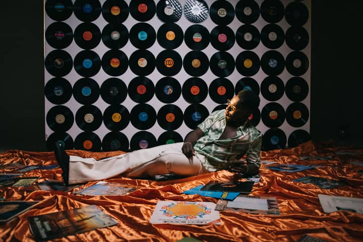 A stylish man lounges amidst vinyl records, evoking a retro and vintage atmosphere.