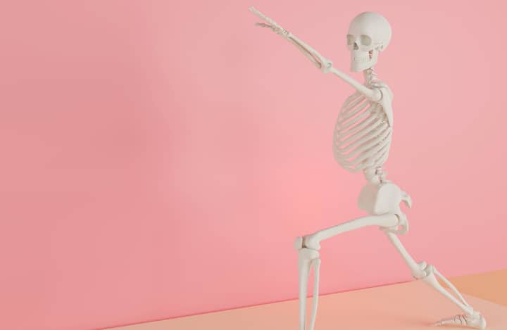 A skeleton model doing a yoga stretch on a pink backdrop, symbolizing fitness and anatomy.