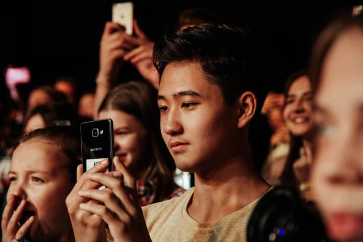 A group of young concert-goers capturing memorable moments with smartphones.