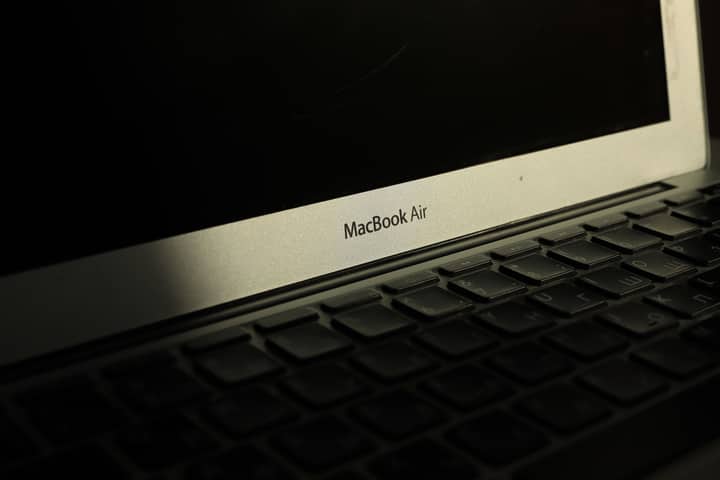 Close-up of a sunlit MacBook Air laptop showcasing its keyboard and screen with shadow effects.