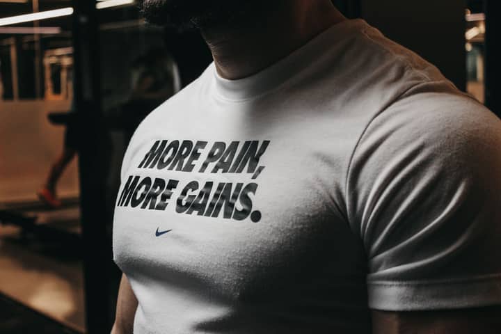 Close-up of a muscular man in the gym wearing a t-shirt with an inspiring fitness message.