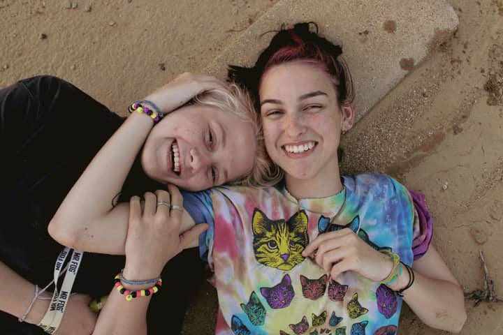 Two smiling women embracing on a sandy beach, exuding joy and relaxation.