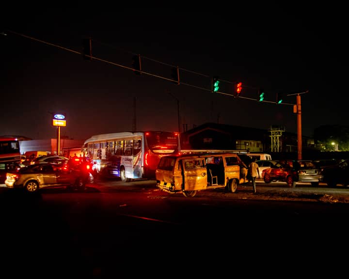 A crowded urban nighttime scene featuring a traffic accident at a busy intersection.