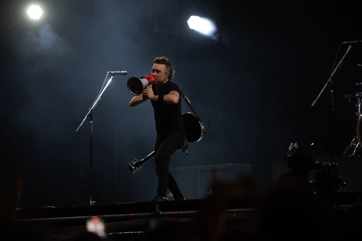 Musician with megaphone on stage during night concert, energizing the crowd.