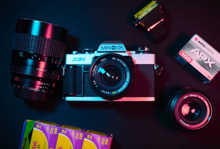 Top view of a Minolta camera surrounded by film rolls and lenses, highlighting retro photography.