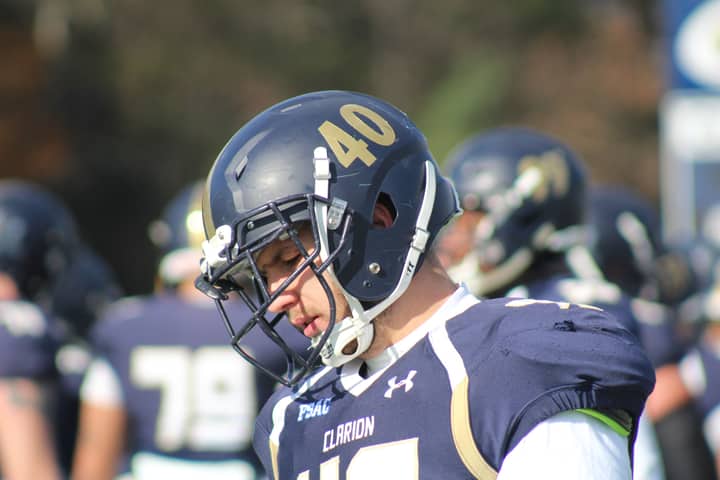 Football player in helmet and uniform focused during outdoor game.