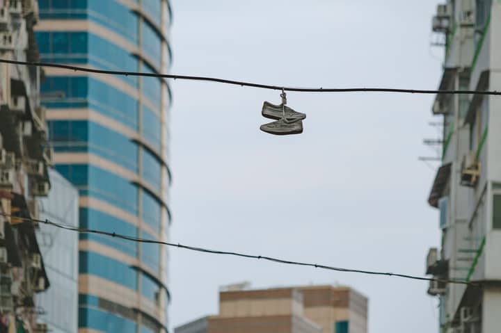 Sneakers hanging on wire amidst Hong Kong skyscrapers, showcasing urban lifestyle and architecture.